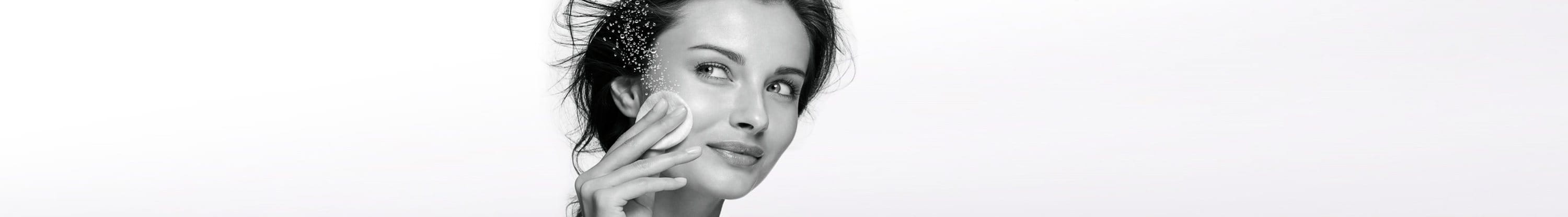 Woman cleans her face with a cotton pad