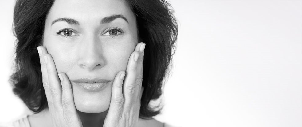 Middle-aged woman touching her cheeks with both hands