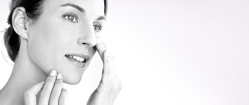 Woman applying cream on her cheek