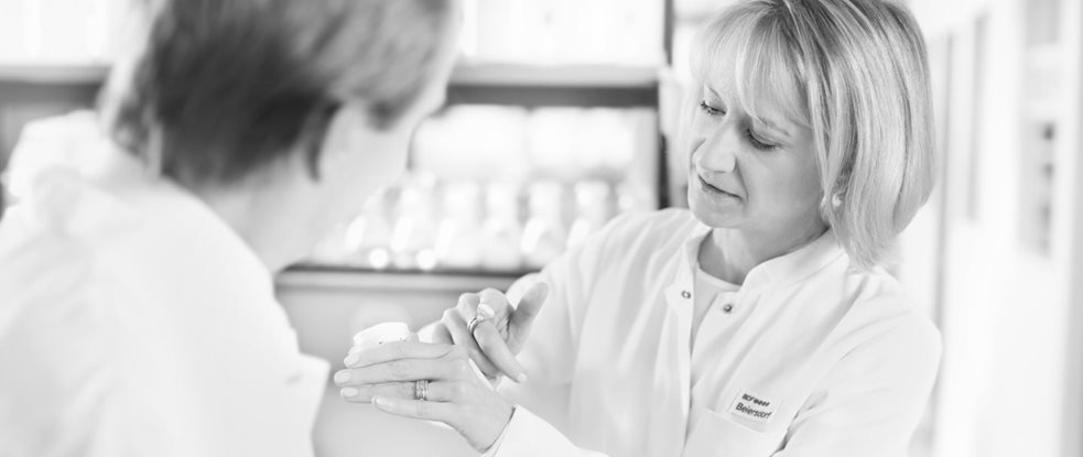 Female scientist is applying cream on the back of her hand - male scientist is watching