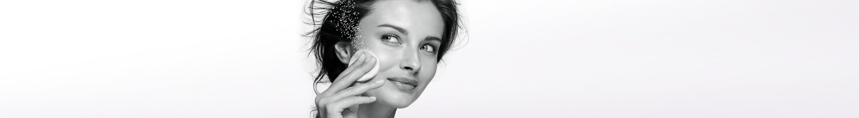Woman cleans her face with a cotton pad