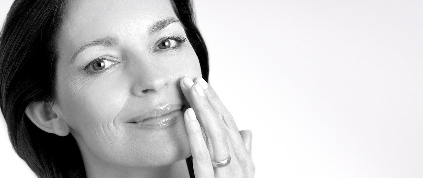 Middle-aged woman touching left cheek with hand