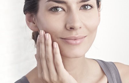 Woman applying cream on her face